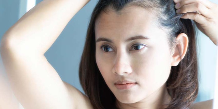 WomanExaminingThinningHair_850x425