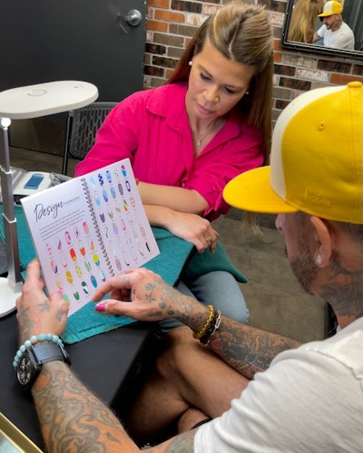 Julie Kandalec and AJ McLean looking at her Nail Art Design Book.