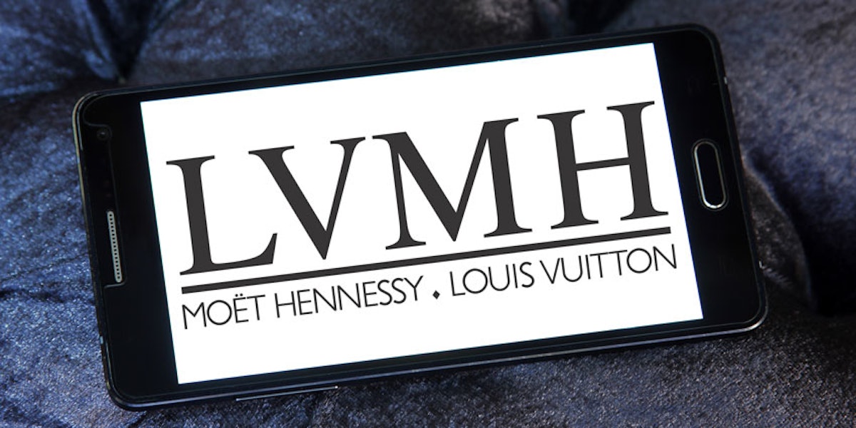 Person holding mobile phone with logo of company LVMH Moet
