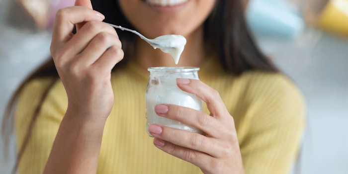 An individual snacks on a yogurt.