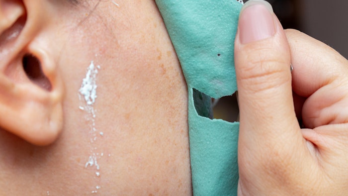 Removing a green cosmetic clay mask from face with freckles