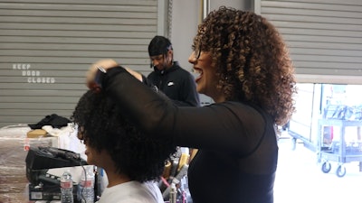 Cosmo Prof Artistic Team Member Brenda Espinosa puts the final touches on her model's voluminous curls on the set of World of Texture in Dallas, Texas.