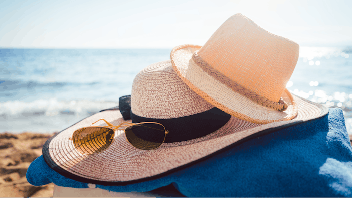 Sun hats and glasses on beach in the sand by the water