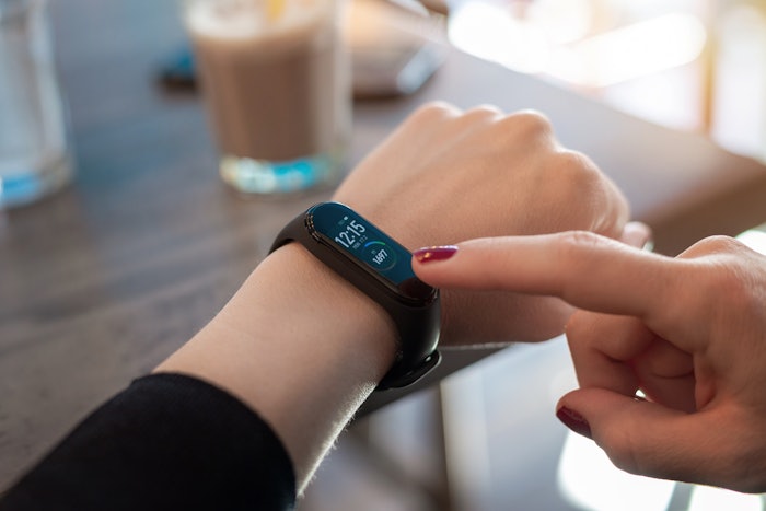Woman use apps on smart bracelet. Touch display with right hand