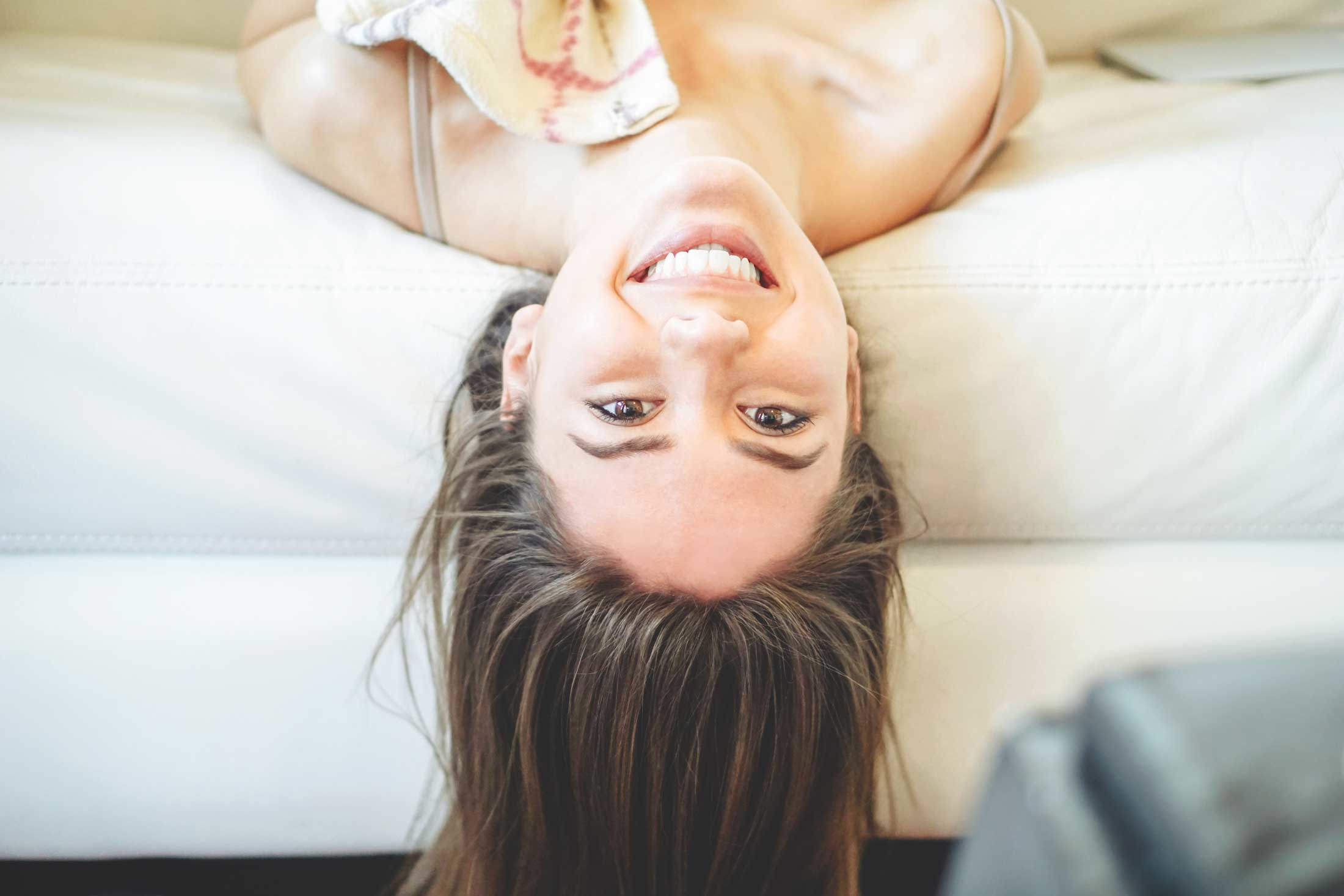 Woman Hanging Upside Down On Couch Smiling