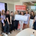 The FusionPKG team delivered a life-sized check for $25,000 to the Lipstick Angels office in California on July 16, 2024. From left: Jo Yang, Kailey McElwee, Samantha Tsang-Lee, Nancy Wang, Eva Ehn, Renata Helfman, Keiko Hartmann, Brianna Filos and Amy Holiber.