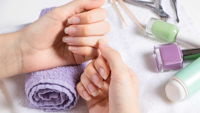 realistic nail manicure hands on towels products and tools in background