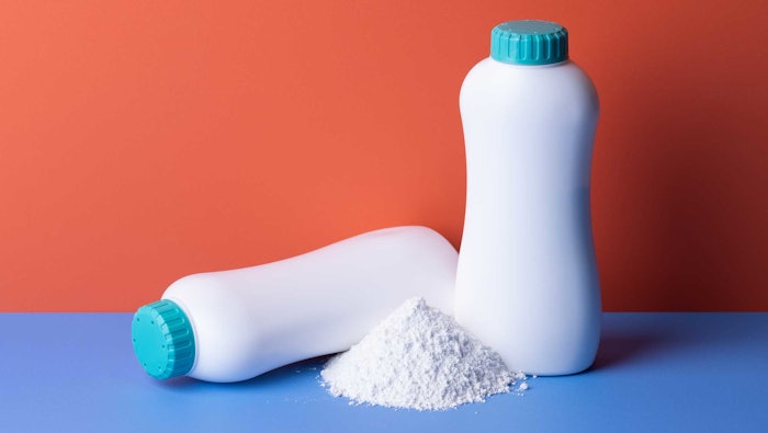 two bottles of talc powder one spilled over blue surface red background AdobeStock_687808176