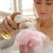 woman in foamy bath pouring body gel into loofah