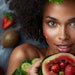 Woman with radiant skin enjoying a healthy meal filled with fresh fruits and vegetables, promoting clear skin from the inside out.