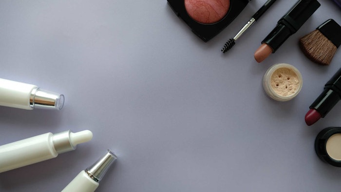 flat display cosmetic makeup lotions laying gray shadowed background