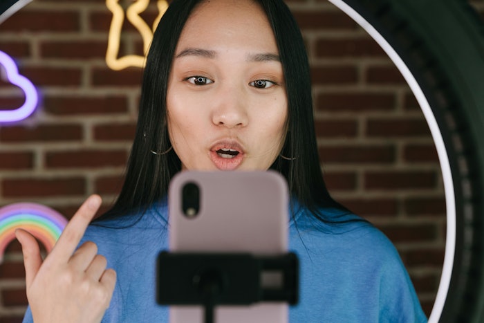 Influencer speaking to phone with ring light.
