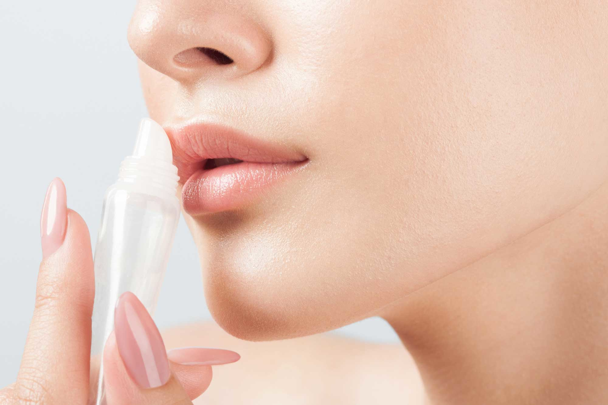 woman applying tube of lip balm only lower half of face shown