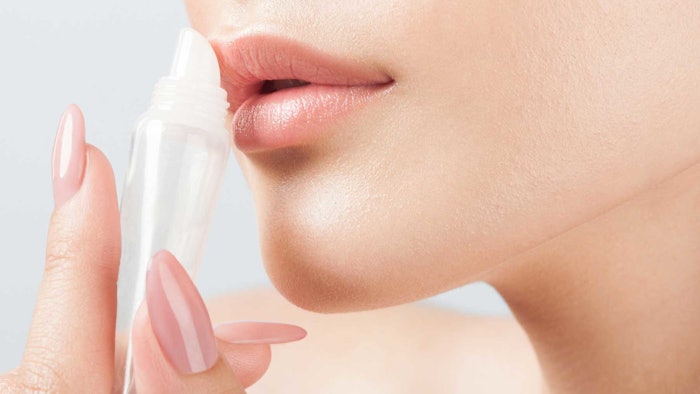 woman applying tube of lip balm only lower half of face shown