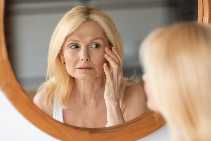 Blond woman checking her face in the mirror.