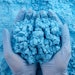 blue powder mixed bulk pile gloved hands holding sample