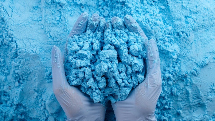 blue powder mixed bulk pile gloved hands holding sample
