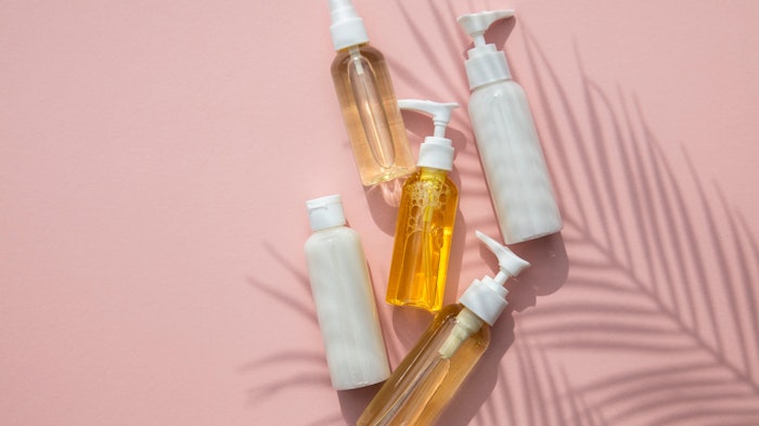 palm shadow bottles of skin care laying on pink background
