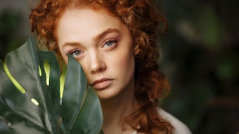 beautiful redhead holding jungle foliage near face