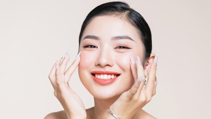 beautiful Asian woman with flawless bright skin smiling hands on face fun nails