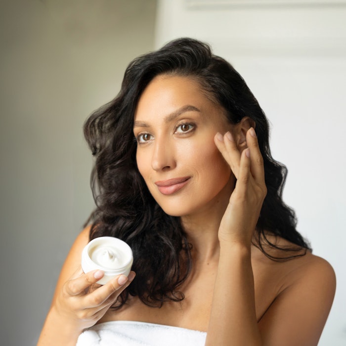 Beautiful Brunette Applying Eye Area Cream Smiling