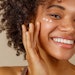 Young Beautiful Multiracial Girl Smiling Using Facial Skin Care
