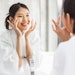 Beautiful Asian Woman Applying Face Cream Bathroom Sink Setting