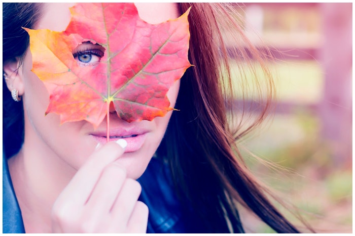 Woman Holding Maple Leaf In Front Of Face Peeking Through Hole Adobe Stock 173772422