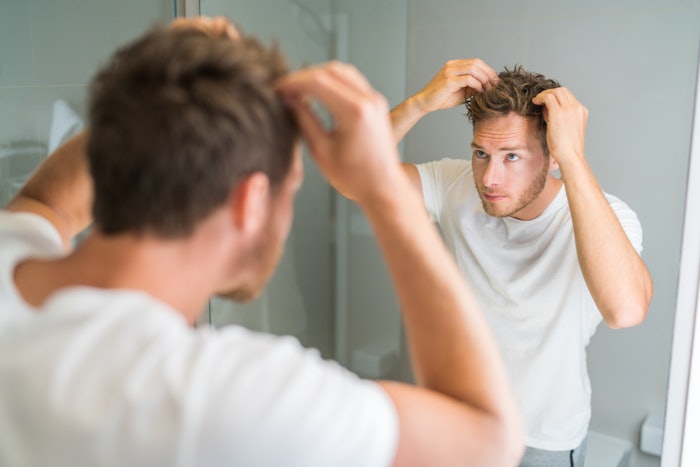 Man Spiking Hair With Hands Looking In Mirror Adobe Stock 167147727