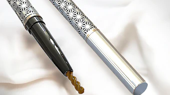 Two metallic precision drill bits with intricate geometric pattern handles
