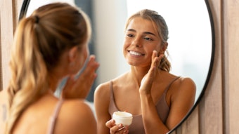 Beautiful Woman In Mirror Applying Facial Skin Cream Adobe Stock 680584299