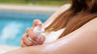 Woman Using Spray Sunscreen Adobe Stock 1563752281