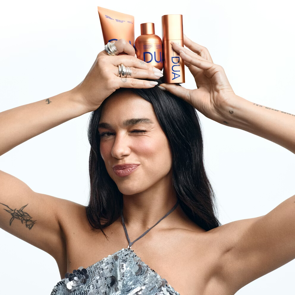 Person balancing beauty products on head, wearing sequined top