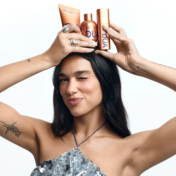 Person balancing beauty products on head, wearing sequined top