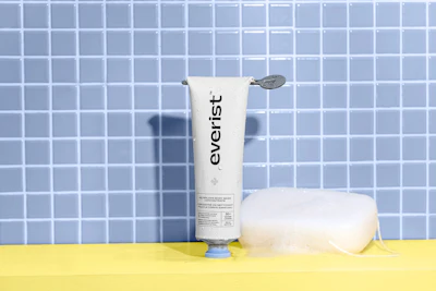 Everist was an early-ish adopter of waterless body care, launching its Waterless Body Wash Concentrate in October 2021, just months after introducing its waterless hair-care concentrates. The water-activated paste-to-lather formula was designed to replace water-heavy, single-use plastic body washes with a concentrated, plant-based format packaged in infinitely recyclable aluminum tubes, targeting lower carbon and plastic-waste impact.