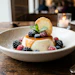 Elegant plated dessert with creamy panna cotta, fresh berries, caramel drizzle, and crispy cookie garnish in fine dining setting