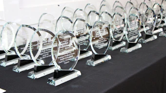 Row of crystal oval awards with engraved plaques displayed on black table