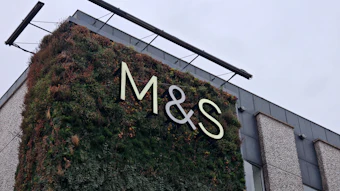 M&S illuminated storefront sign on ivy-covered building facade with modern architecture