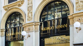 Giorgio Armani luxury storefront with ornate gold-trimmed arched windows and black balconies on an elegant white building facade