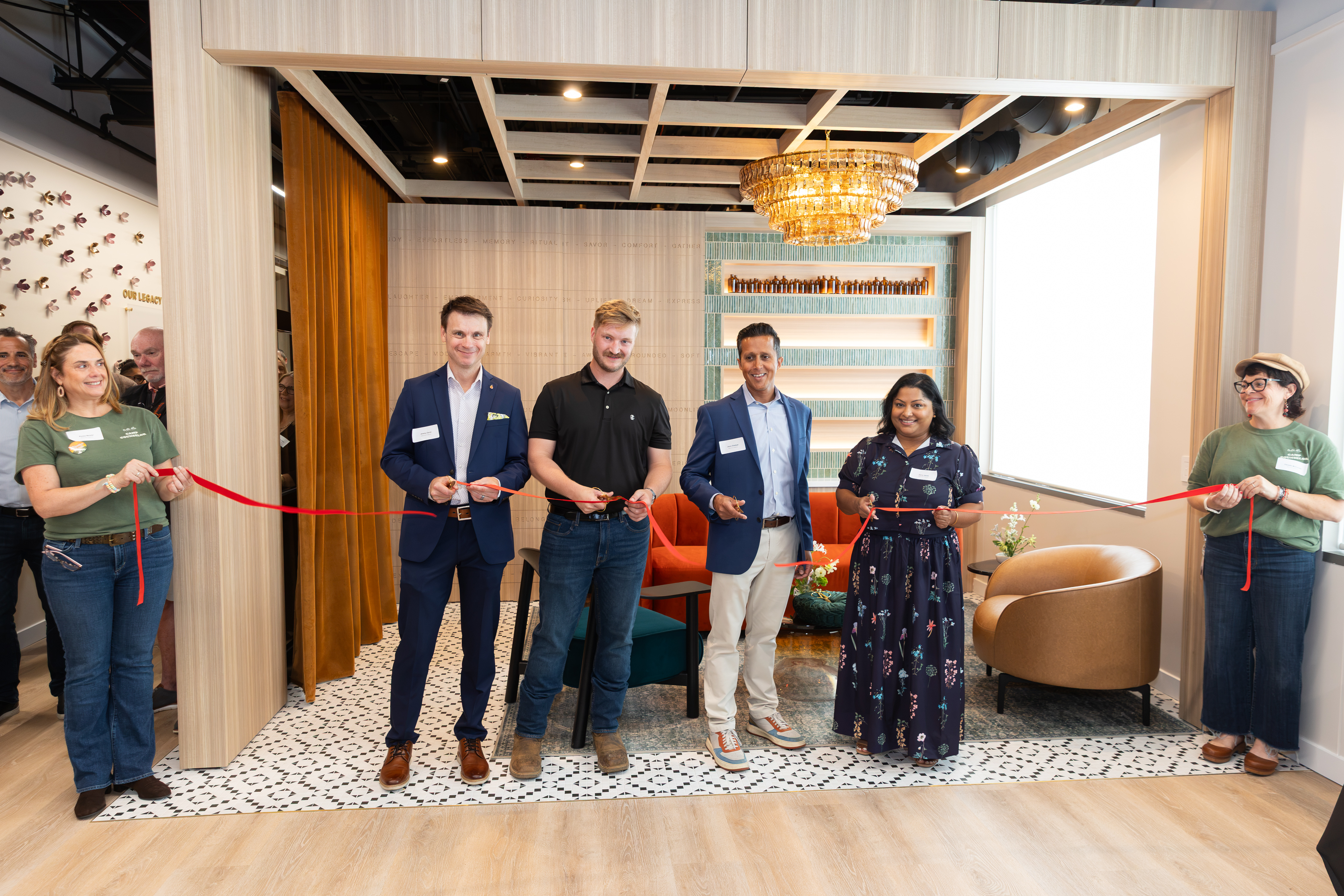 Group of professionals holding red ribbon at indoor ribbon-cutting ceremony in modern office space