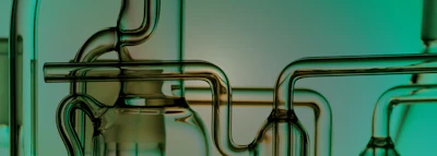 Laboratory glassware with curved metallic tubing and glass vessels against turquoise background