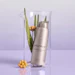 Epionce Ultra Refining Lytic Serum bottle displayed in clear cylinder with green plant stems and yellow flowers on lavender background