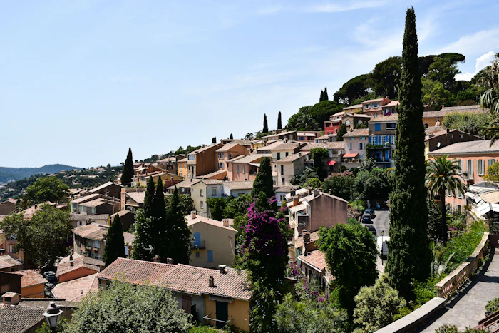 Hillside Mediterranean village with terracotta buildings, cypress trees, and colorful facades overlooking coastal landscape