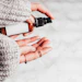 Person in gray knit sweater holding amber dropper bottle with black spray nozzle against snowy background