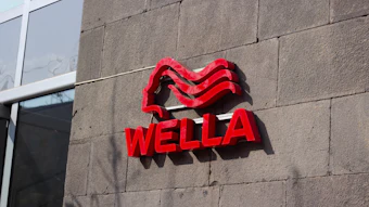 Wella red neon logo sign mounted on concrete building wall