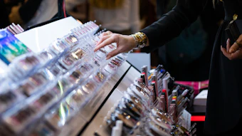 Person browsing cosmetic products displayed on retail counter with multiple colorful beauty items