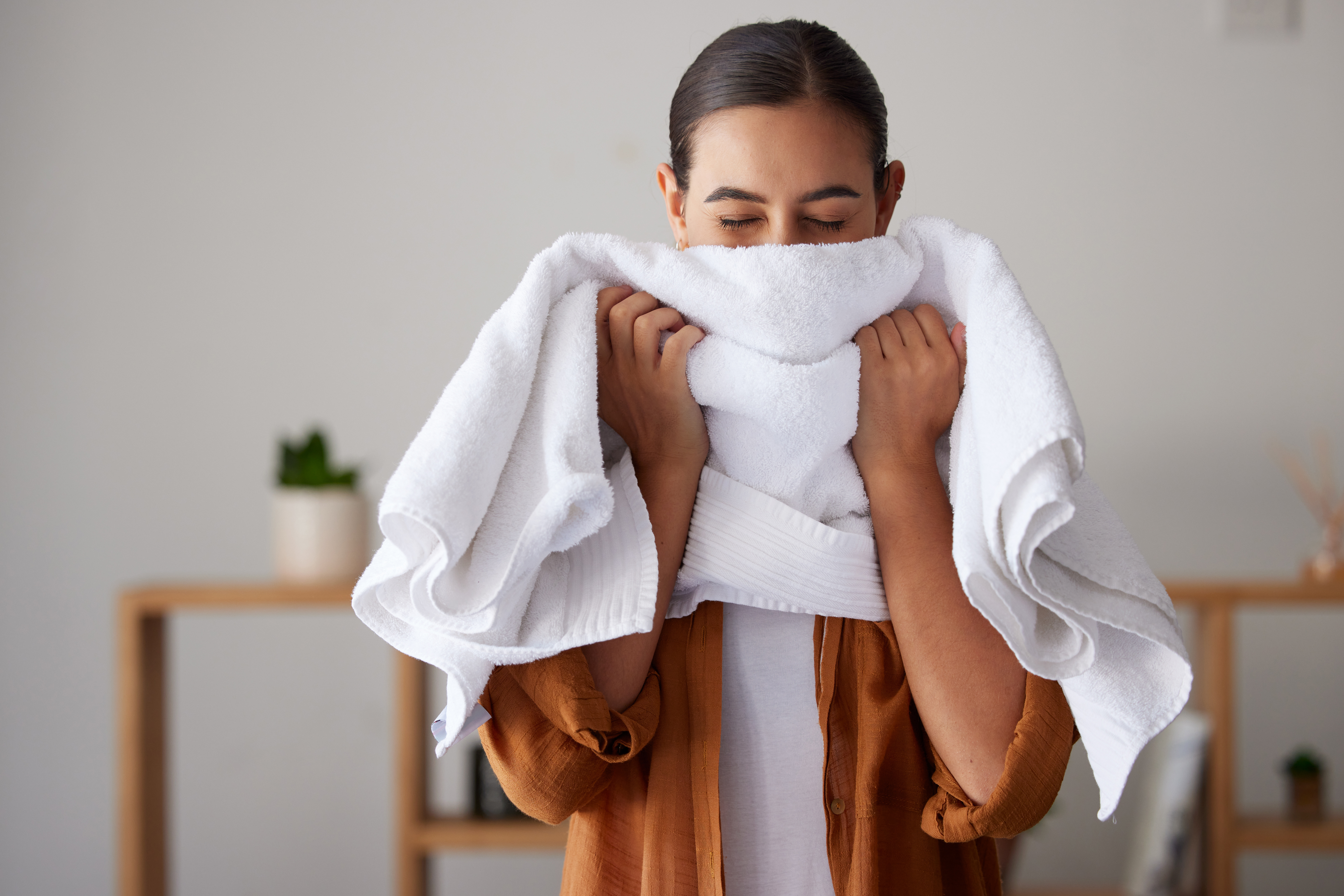 Woman wrapping white towel around herself in spa setting wearing brown robe