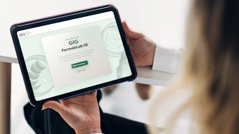 Person holding tablet displaying GIG FormulaLab IQ website with green call-to-action button
