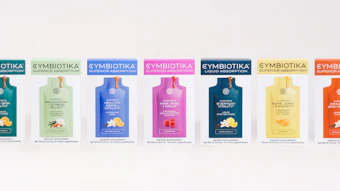 Cymbiotika supplement product line featuring seven colorful wellness formulas in teal, green, blue, magenta, navy, yellow, and orange packaging.