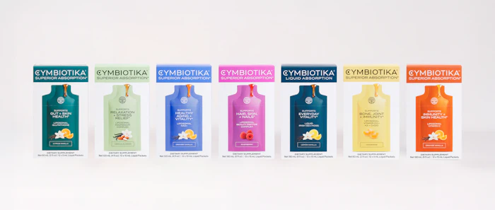Cymbiotika supplement product line featuring seven colorful wellness formulas in teal, green, blue, magenta, navy, yellow, and orange packaging.